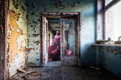 eine unter einem tuch verhüllte person wandert duch verfallene gänge.